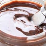 Close up shot of homemade keto Nutella in a glass jar with a butter knife in it.