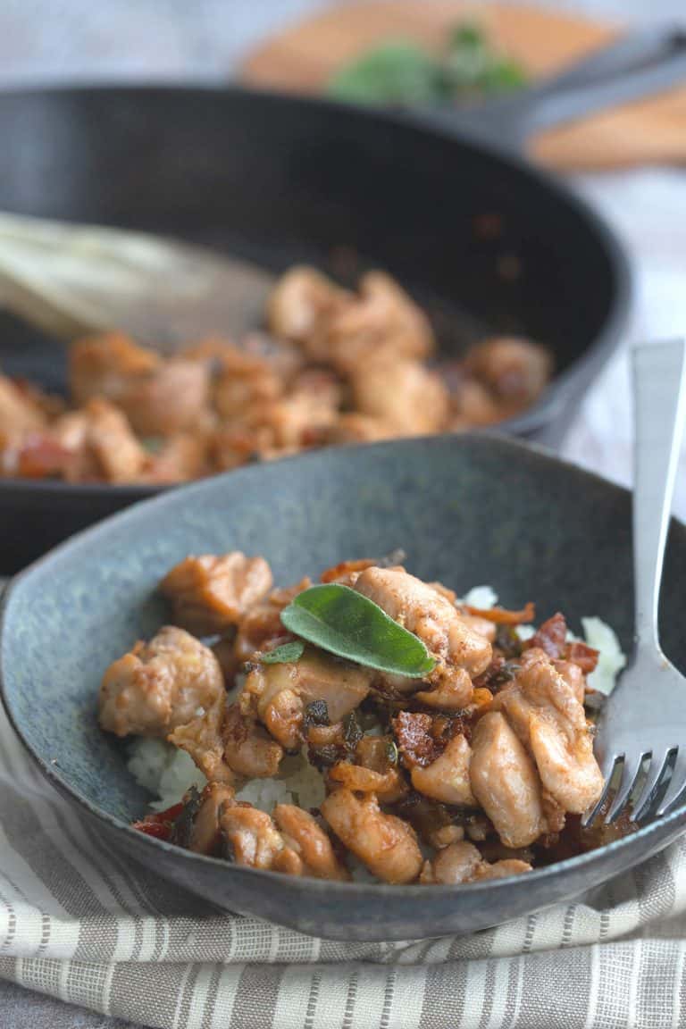 A black bowl filled with Brown Butter Chicken and cauliflower rice.