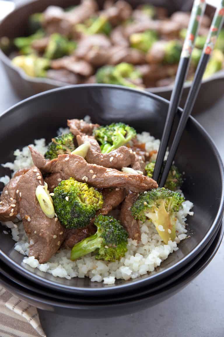 Keto Beef and Broccoli over cauliflower rice in a black bowl.