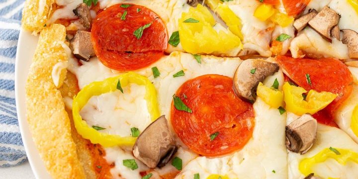 Top view of a keto pizza topped with pepperoni, mushrooms and banana peppers