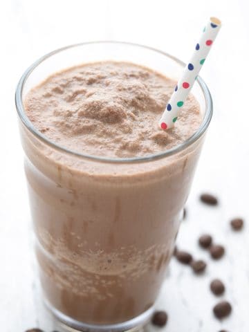 Close up shot of a Keto Coffee Protein Shake in a tall glass with a straw.