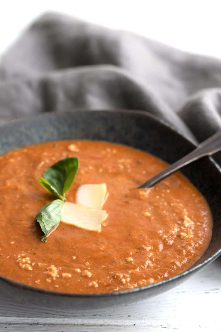 Close up shot of a bowl of Roasted Tomato Soup with basil and Parmesan.