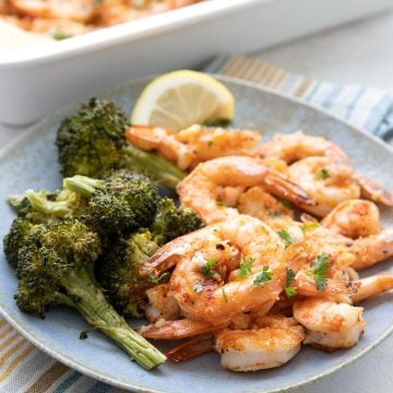 Parmesan Garlic Baked Shrimp on a blue plate with roasted broccoli.