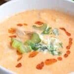 Close up shot of a bowl of Buffalo chicken soup with chopped celery and crumbled bleu cheese on top.