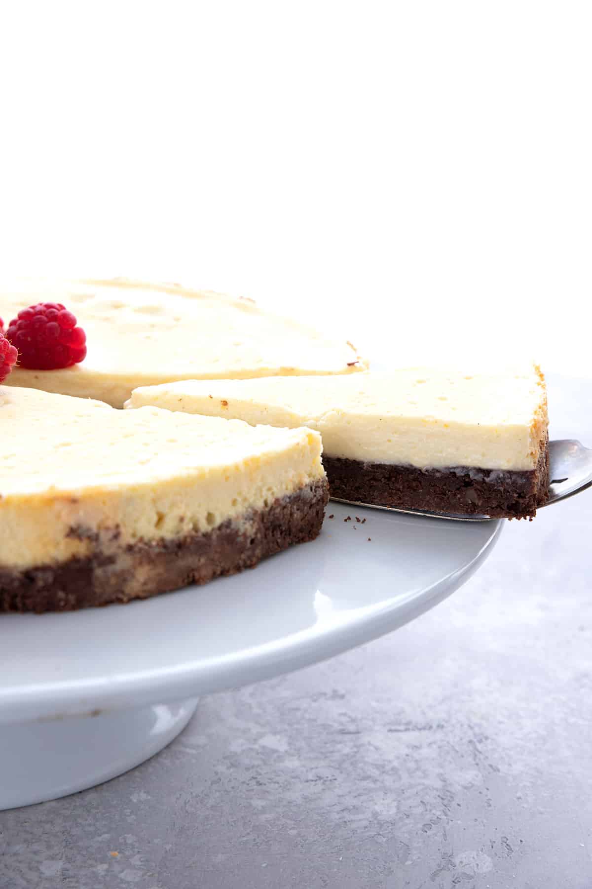 A slice of Keto Brownie Cheesecake being pulled away from the main cake.
