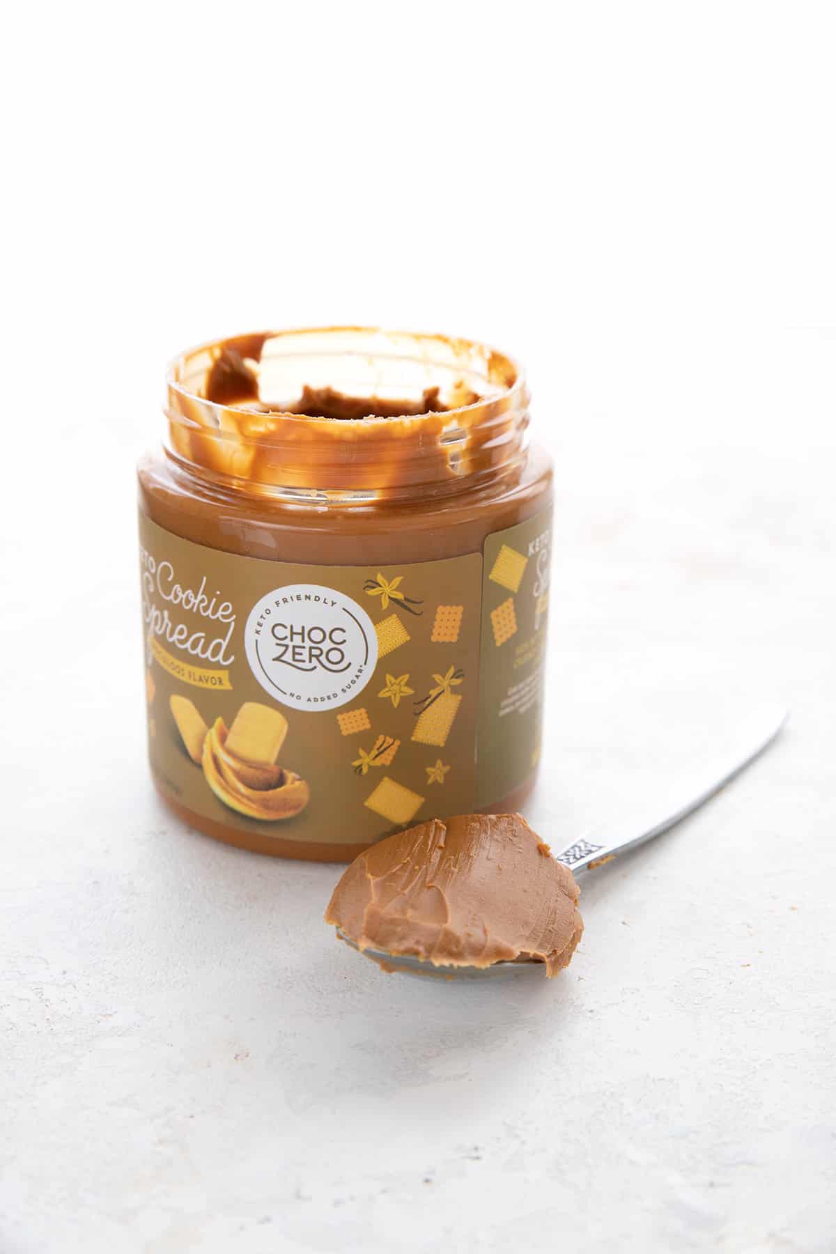 A jar of keto cookie butter spread with a spoonful in front.