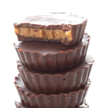 A stack of keto peanut butter cups with a bite taken out of the top one.