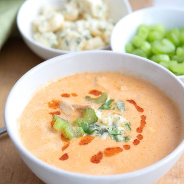 A bowl of Buffalo Chicken Soup on a cutting board with celery and bleu cheese in the background.