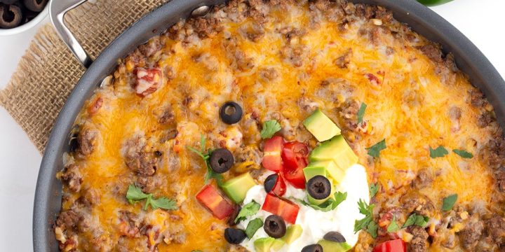 Top down image of Mexican Cauliflower Rice in a large skillet, with avocado, cilantro, jalapeno and olives all around.