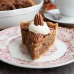 A slice of keto pecan pie sitting on a plate with whipped cream on top.