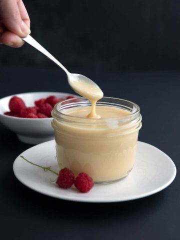 A spoon drizzling Sugar Free Sweetened Condensed Milk into a jar.