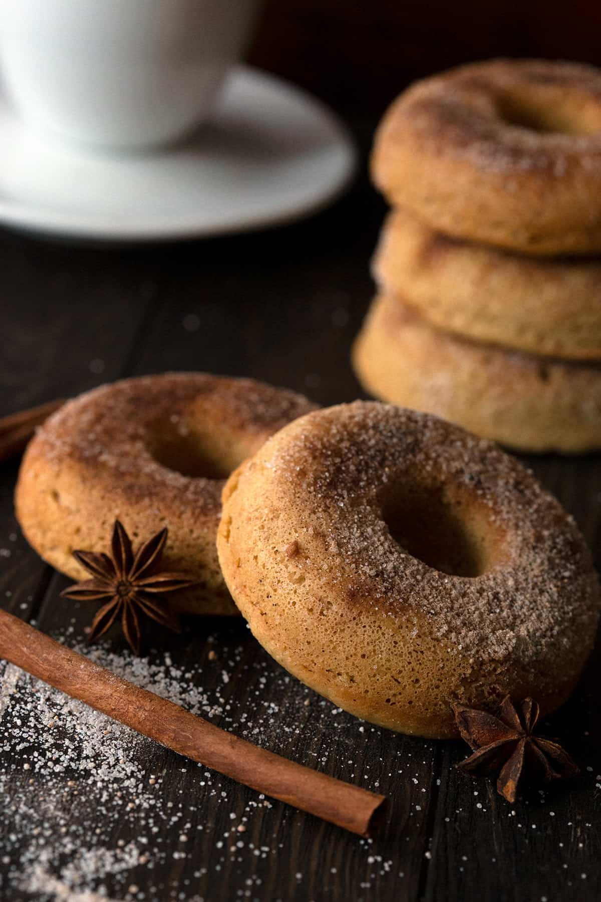 Close up shot of two keto chai spice donuts on a brown table with cinnamon sticks and star anise.
