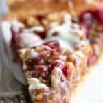 Titled image of a slice of Keto Cranberry Walnut Tart on a white plate with a fork.