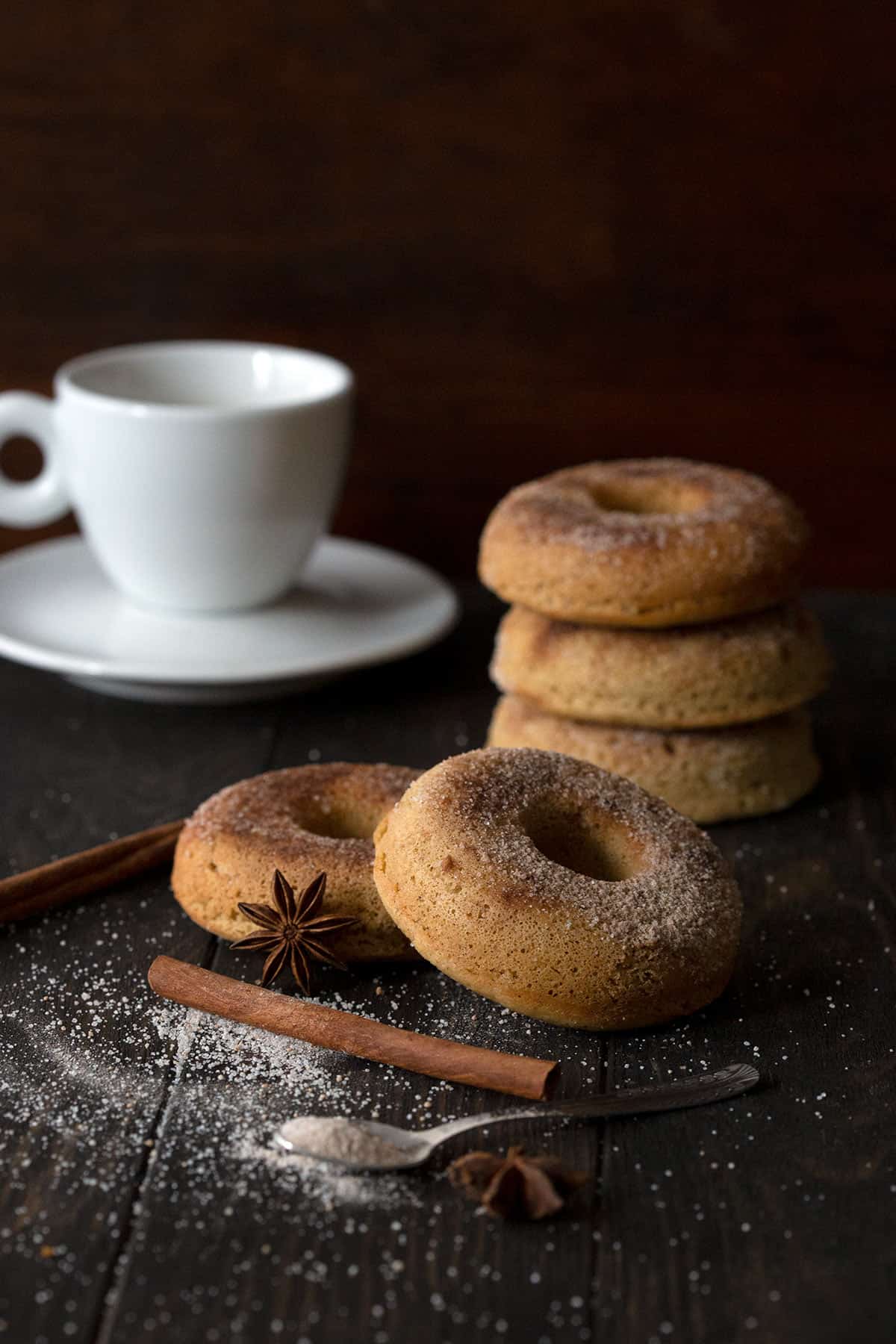 Keto Almond Flour Donuts with Cinnamon Sugar Coating on a brown table with a cup of coffee in the background.