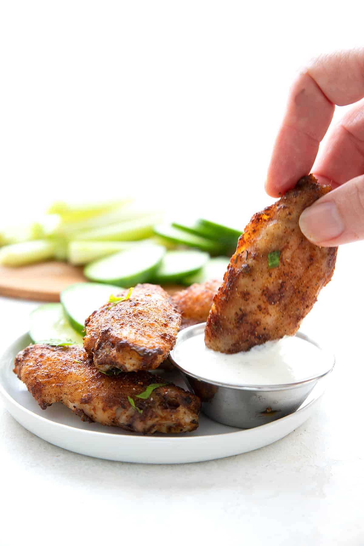 A hand dipping a Cajun wing into ranch dressing.
