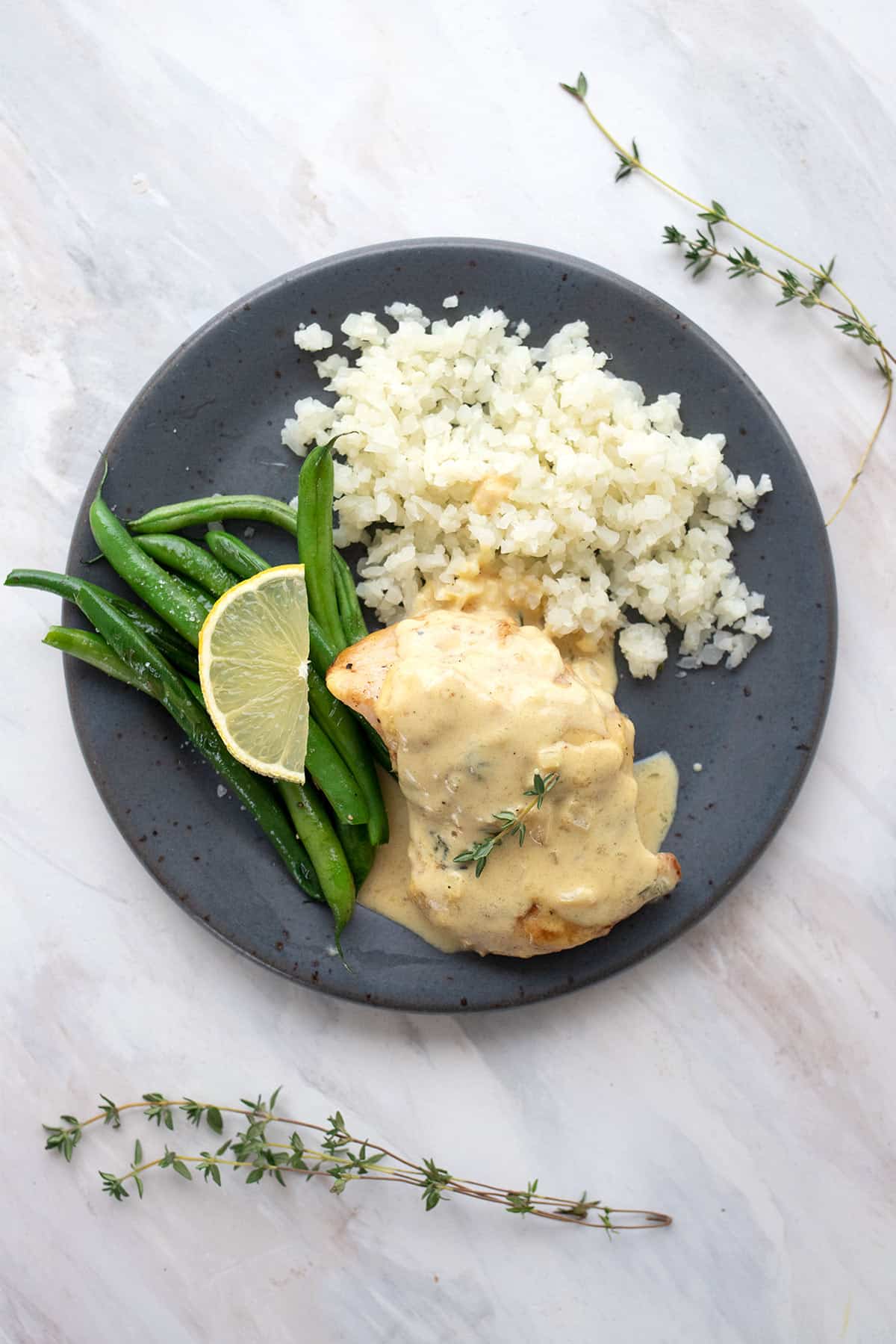 Top down image of a plate of Chicken Dijon with cauliflower rice and green beans.