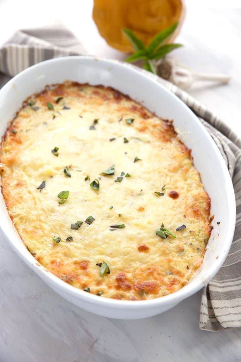 Spaghetti Squash Casserole in a white oval baking dish with a striped grey napkin.