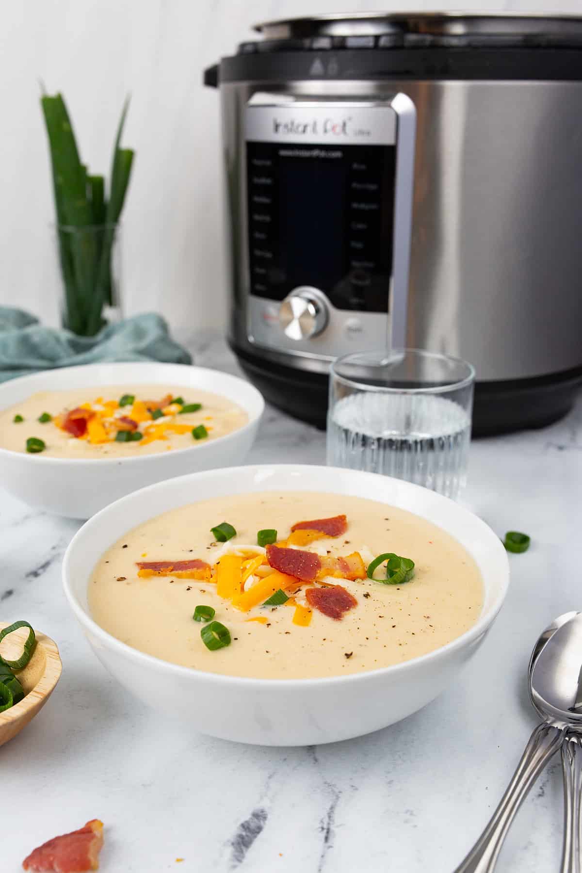Two bowls of Loaded Cauliflower Soup in front of an Instant Pot.