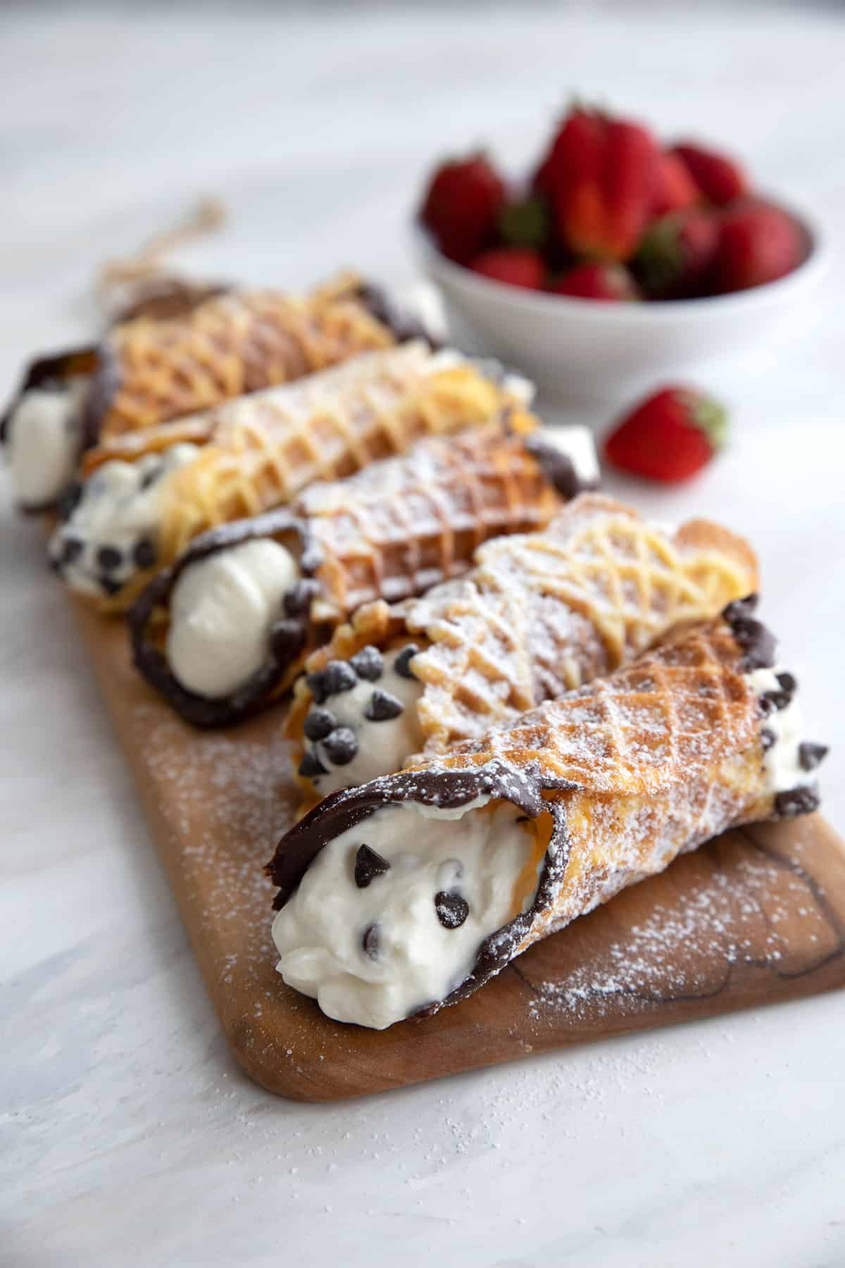 Keto cannoli made with pizzelle shells on a wooden cutting board.