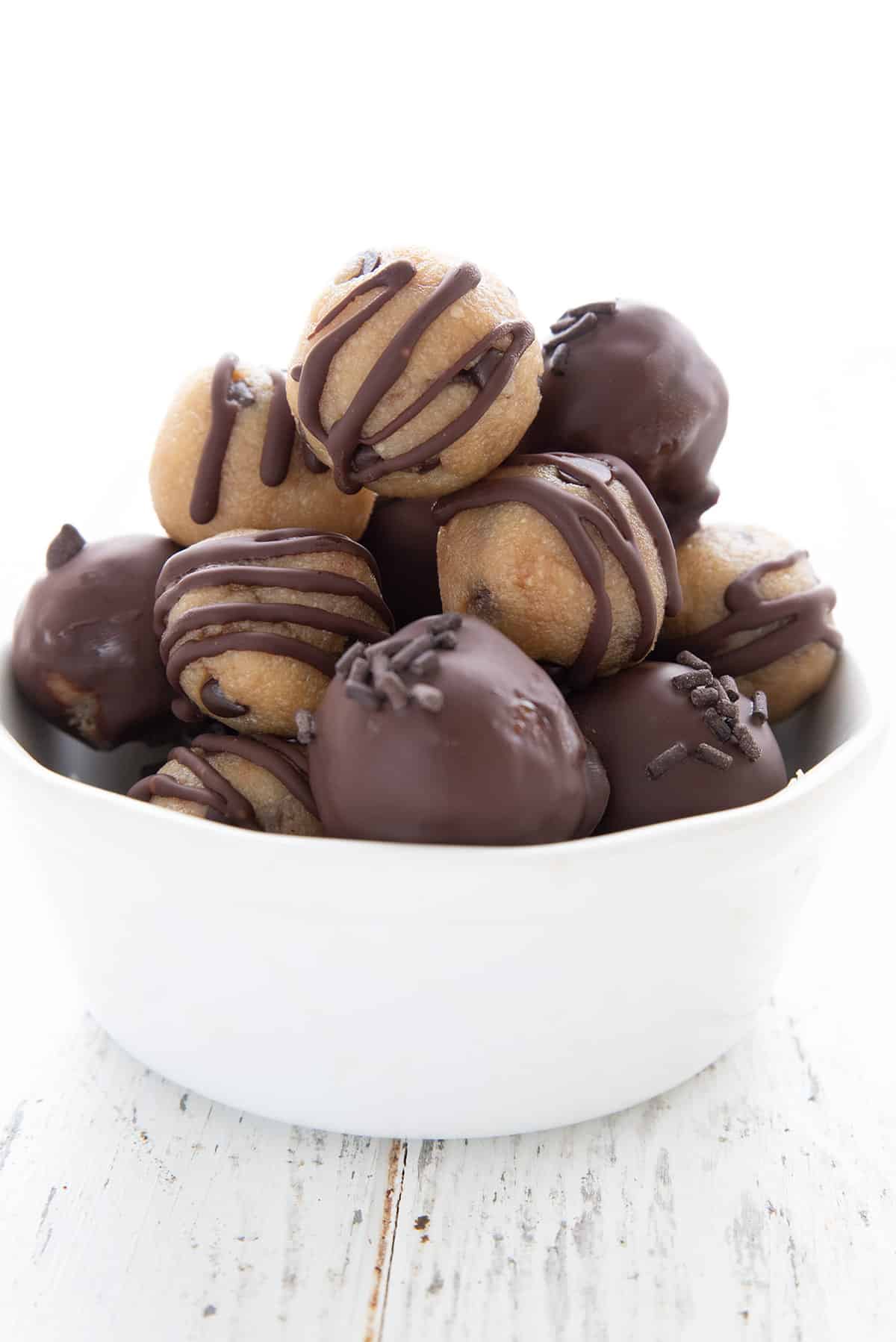 A white bowl filled with keto cookie dough troubles dipped in chocolate.