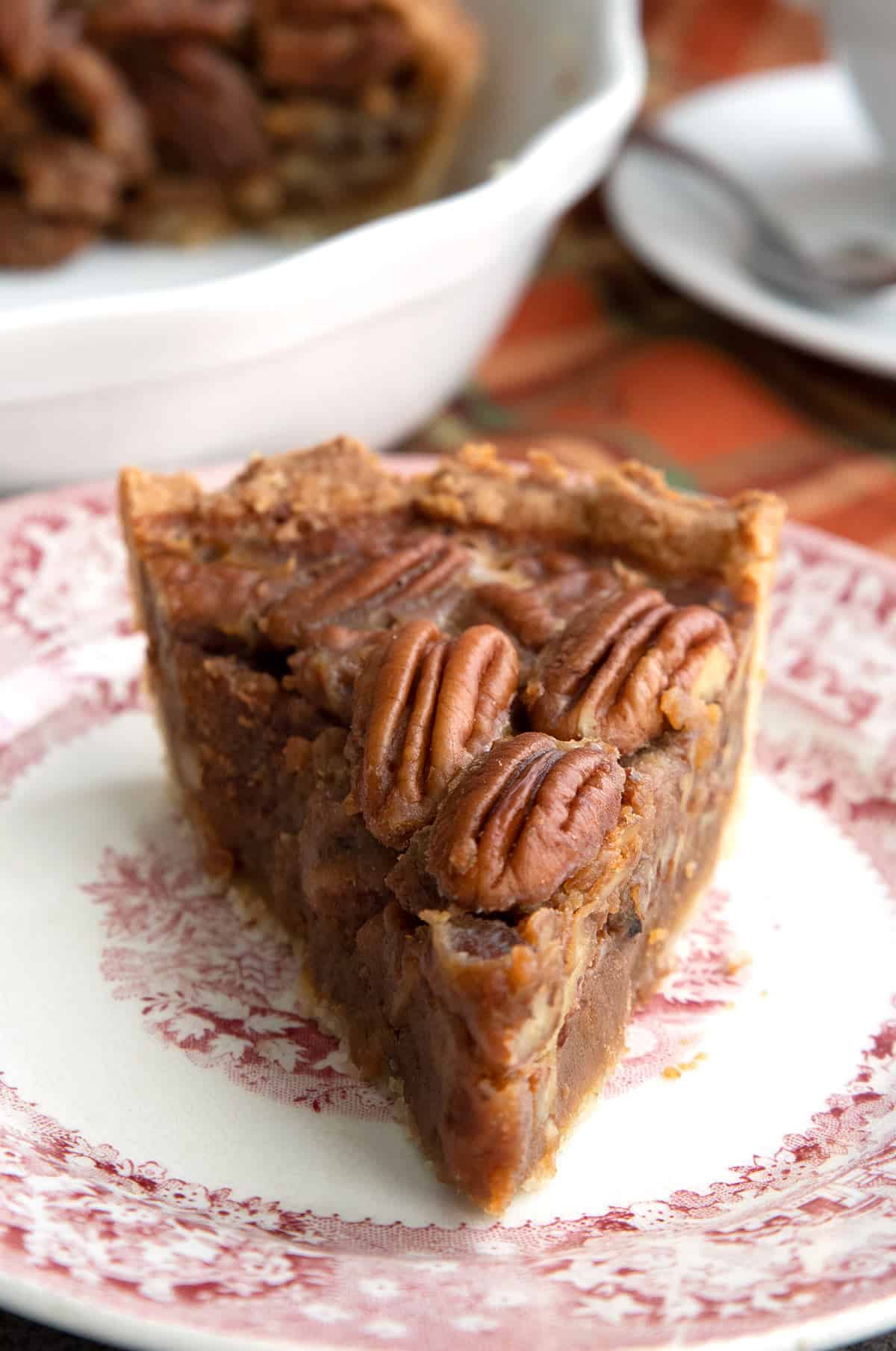 Close up shot of a slice of keto pecan pie on a red patterned plate.