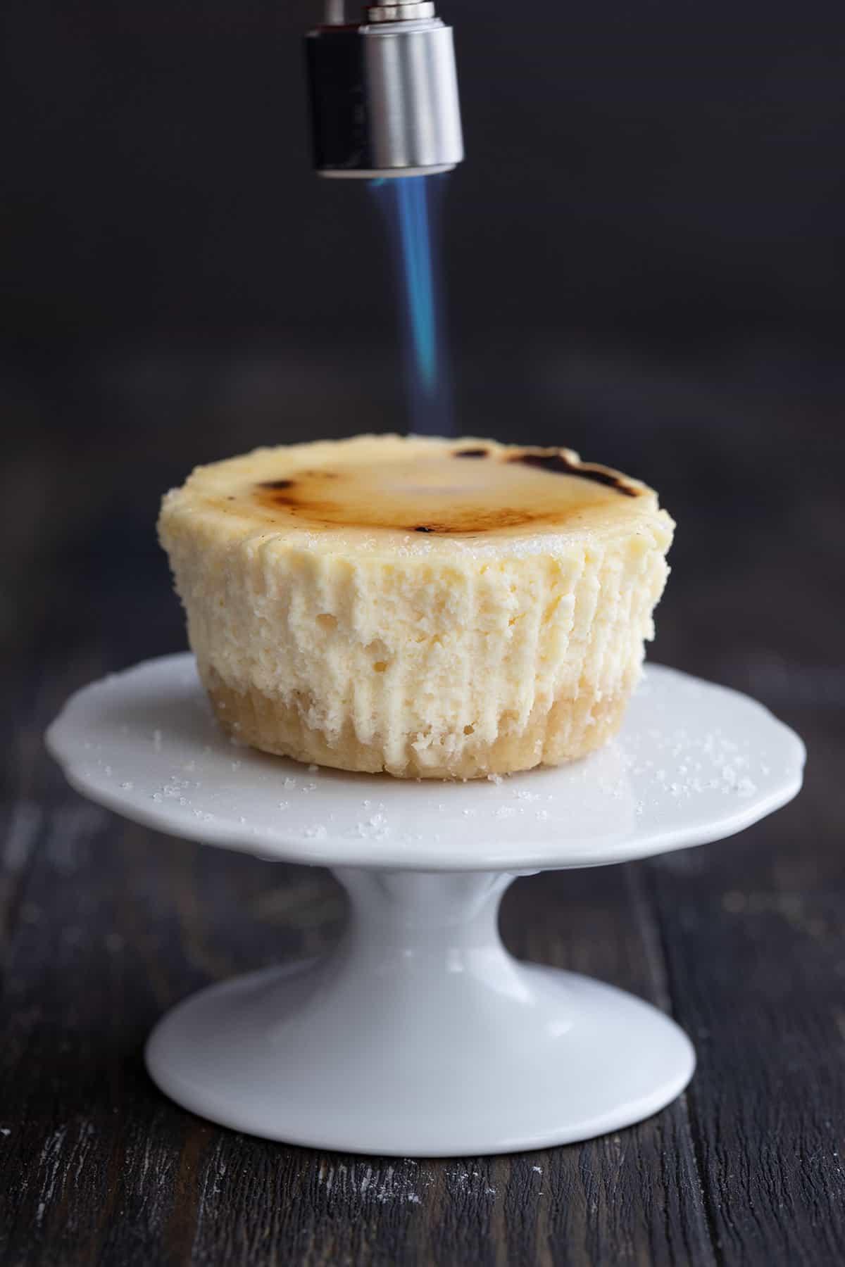 A keto mini cheesecake with a lit kitchen torch above it. 