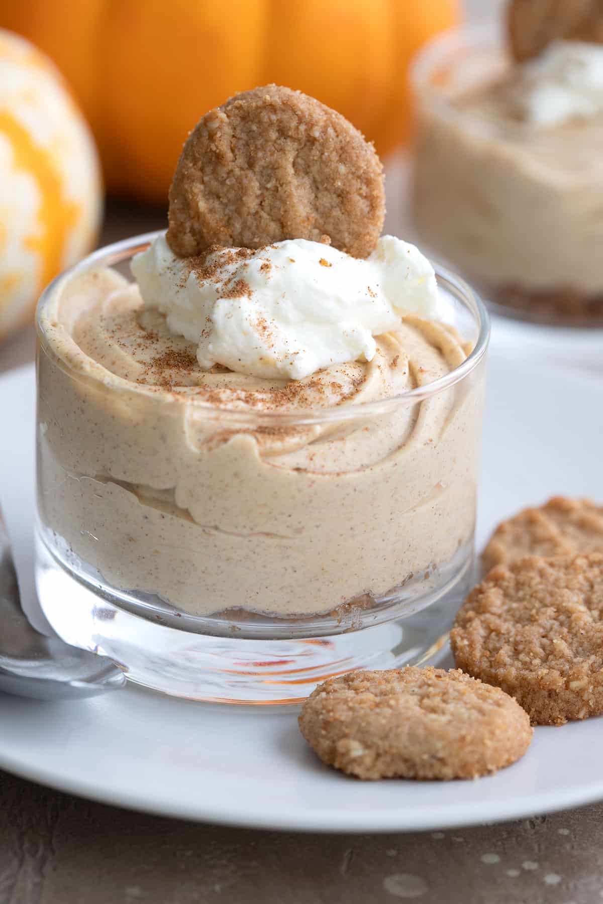 A glass dessert cup filled with Easy Keto Pumpkin Cheescake on a white plate.