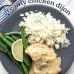 Top down image of Creamy Chicken Dijon on a dark grey plate with cauliflower rice and green beans.