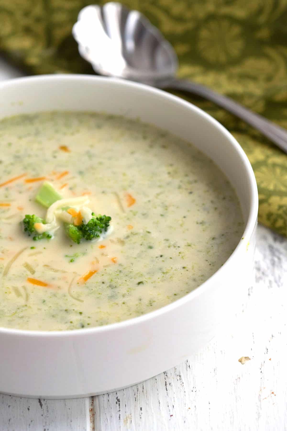 Close up shot of keto broccoli cheese soup in a white bowl with a green napkin.