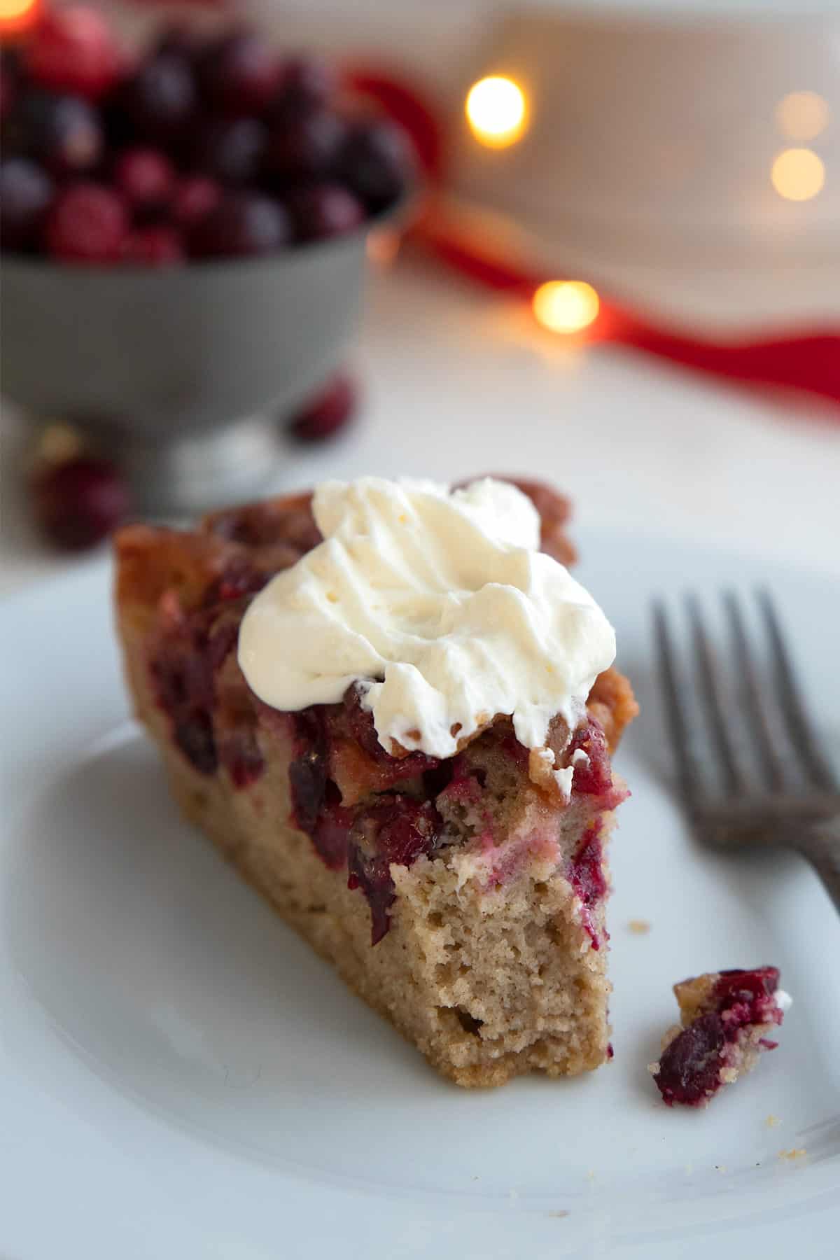 A slice of Keto Cranberry Upside Down Cake with whipped cream on top.