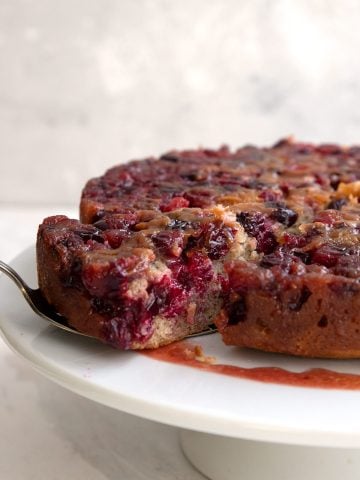 Cranberry Upside Down Cake with a slice being pulled away with a cake lifter.