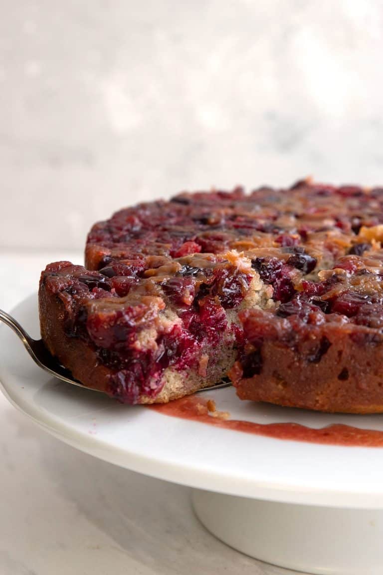 Cranberry Upside Down Cake with a slice being pulled away with a cake lifter.