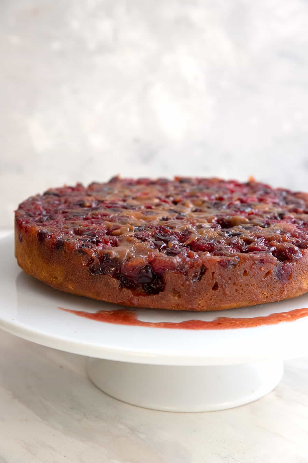 Cranberry Upside Down Cake on a white cake stand.