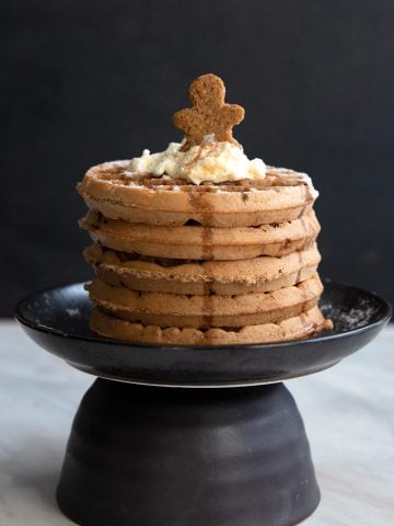 Keto Gingerbread Waffles in a stack on a black plate.