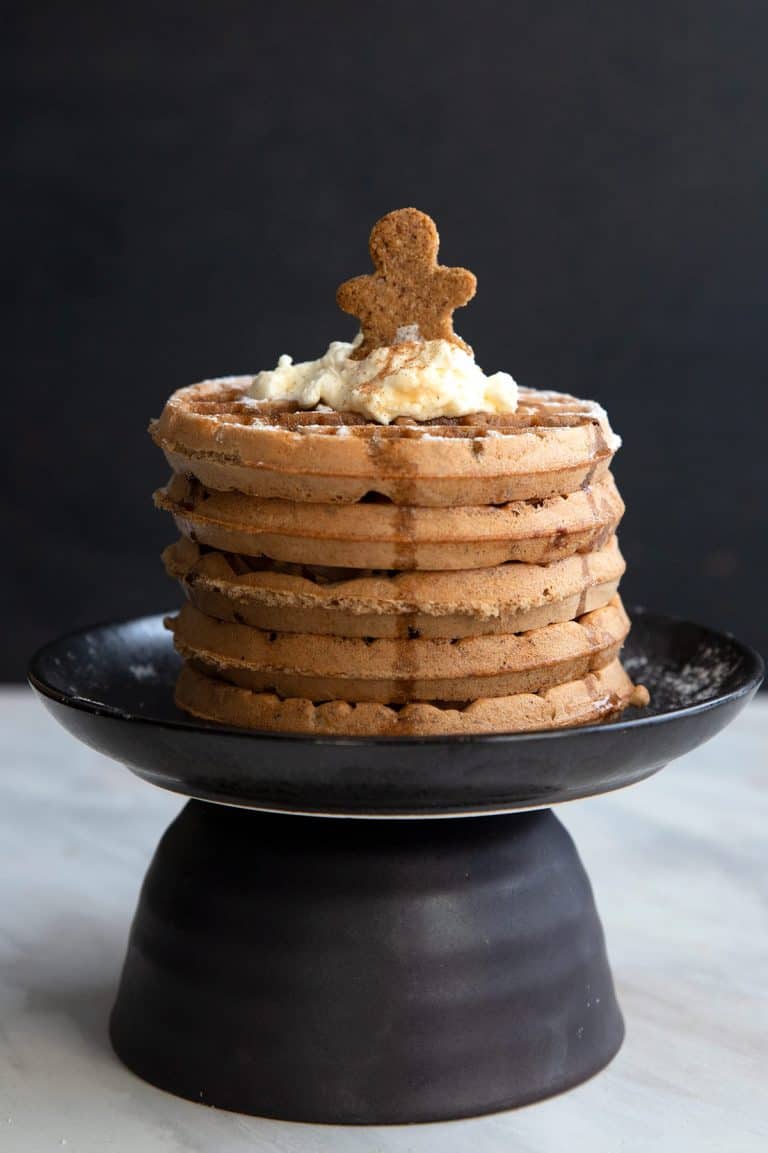 Keto Gingerbread Waffles in a stack on a black plate.