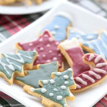 Keto sugar cookies with colorful royal icing on a white plate over a plaid napkin.