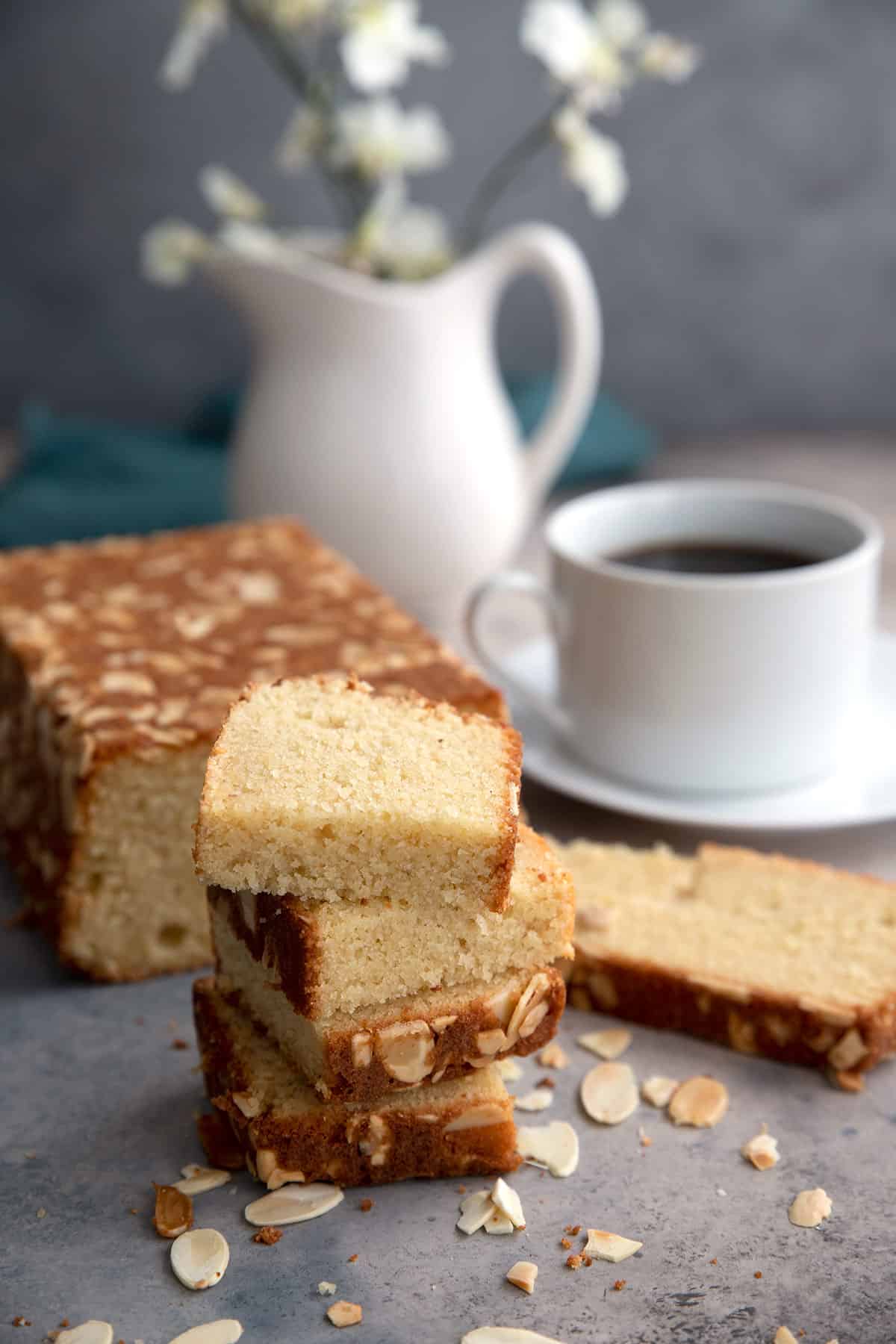 Slices of almond flour loaf cake stacked in front of the remaining cake.