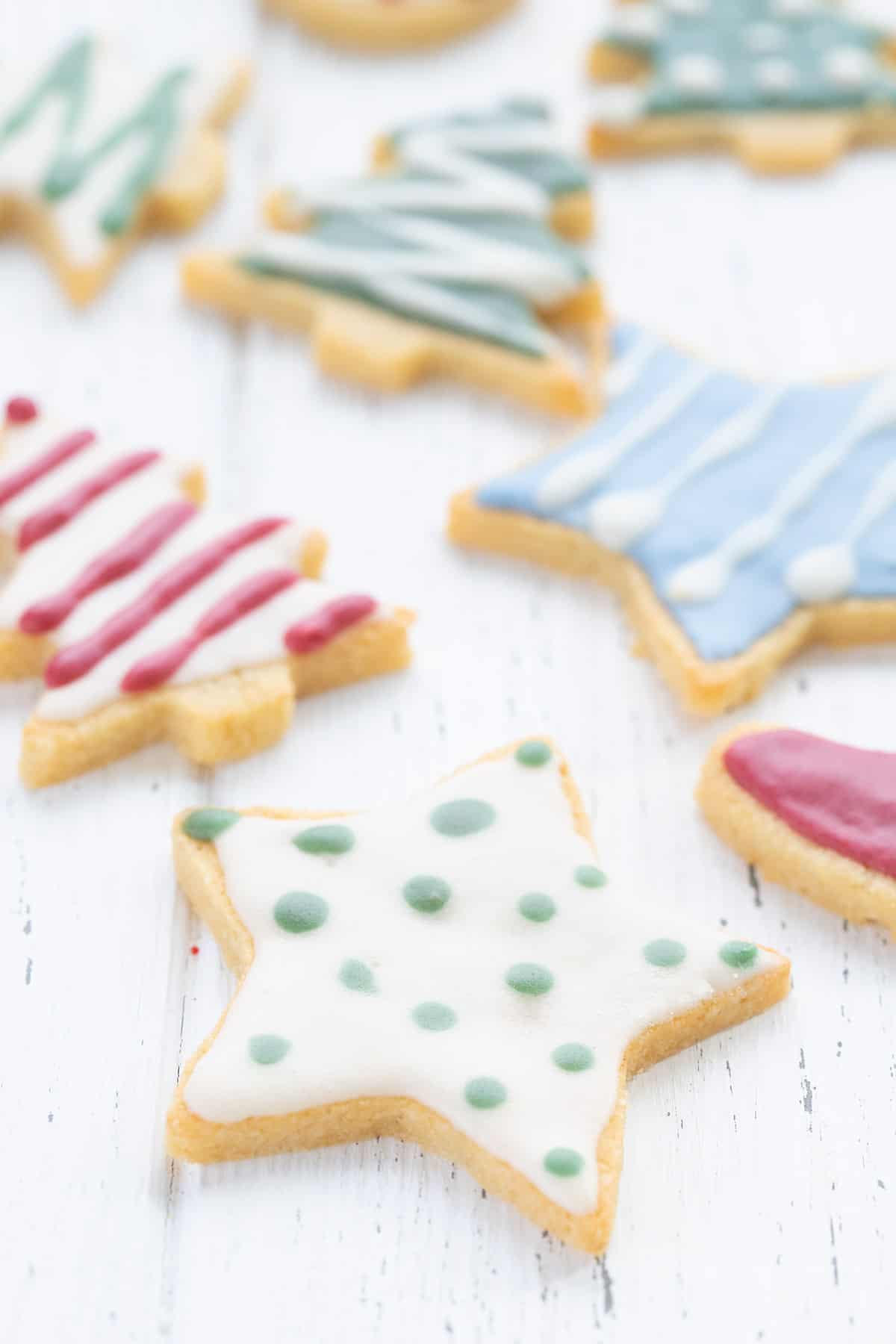 Decorated keto sugar cookies laid out on a white wooden table.