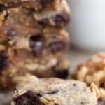 Titled Pinterest image of a keto walnut chocolate chunk blondie on a brown table with a bite taken out of it.