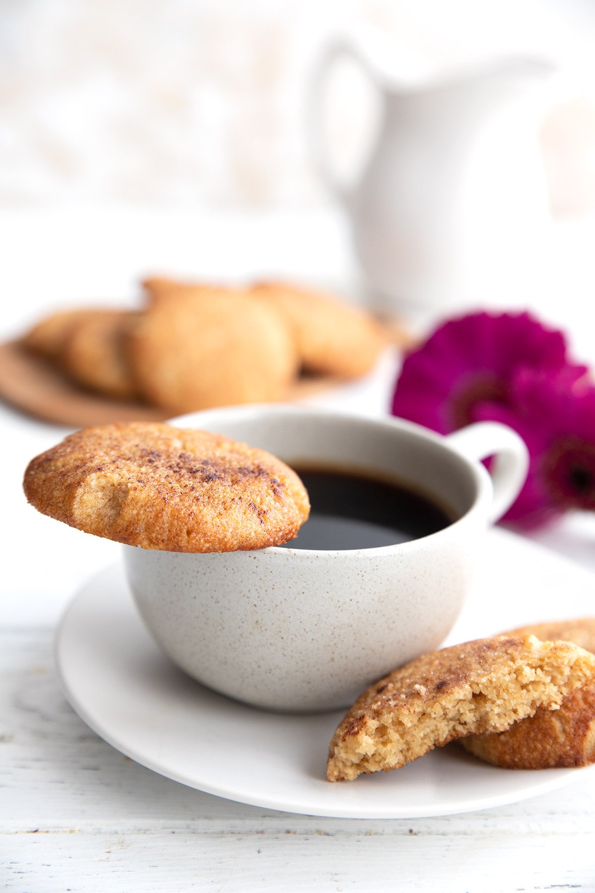 A keto snickerdoodle cookie rests on the edge of a coffee cup.