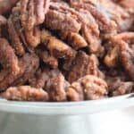 Titled image of keto candied pecans piled up on a metal cake stand.