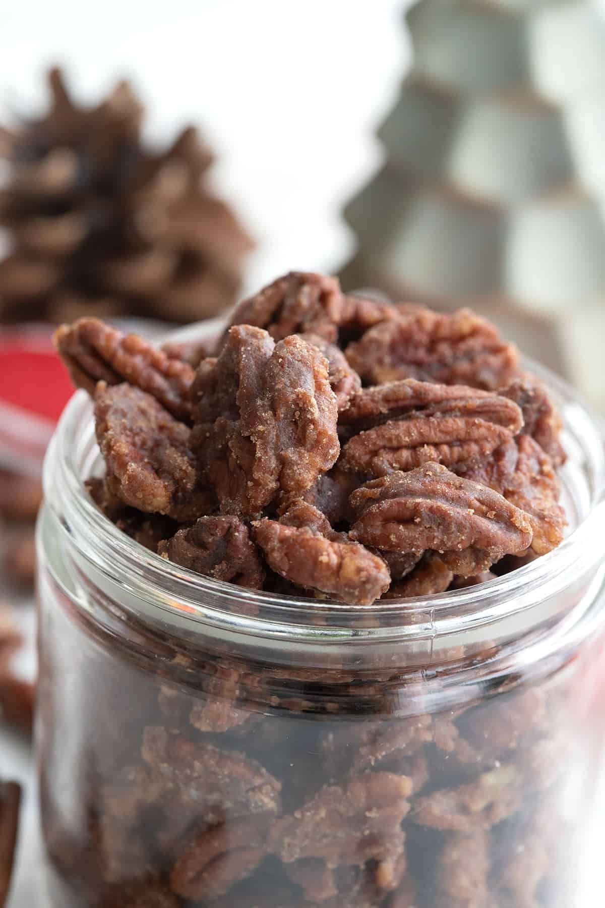 Close up shot of keto candied pecans in a glass jar.