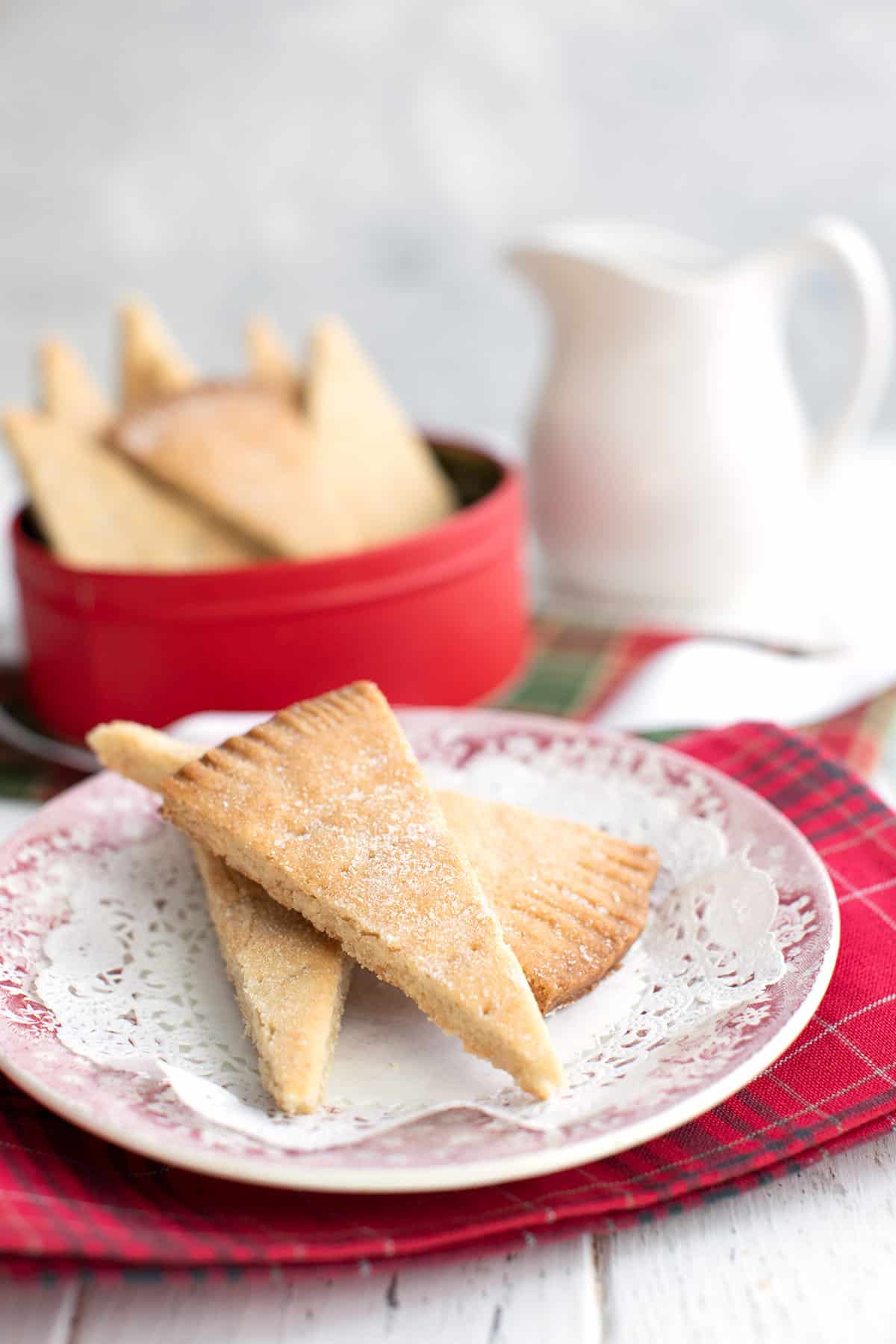 Sugar free keto shortbread cookies piled on a plate over a red patterned napkin.