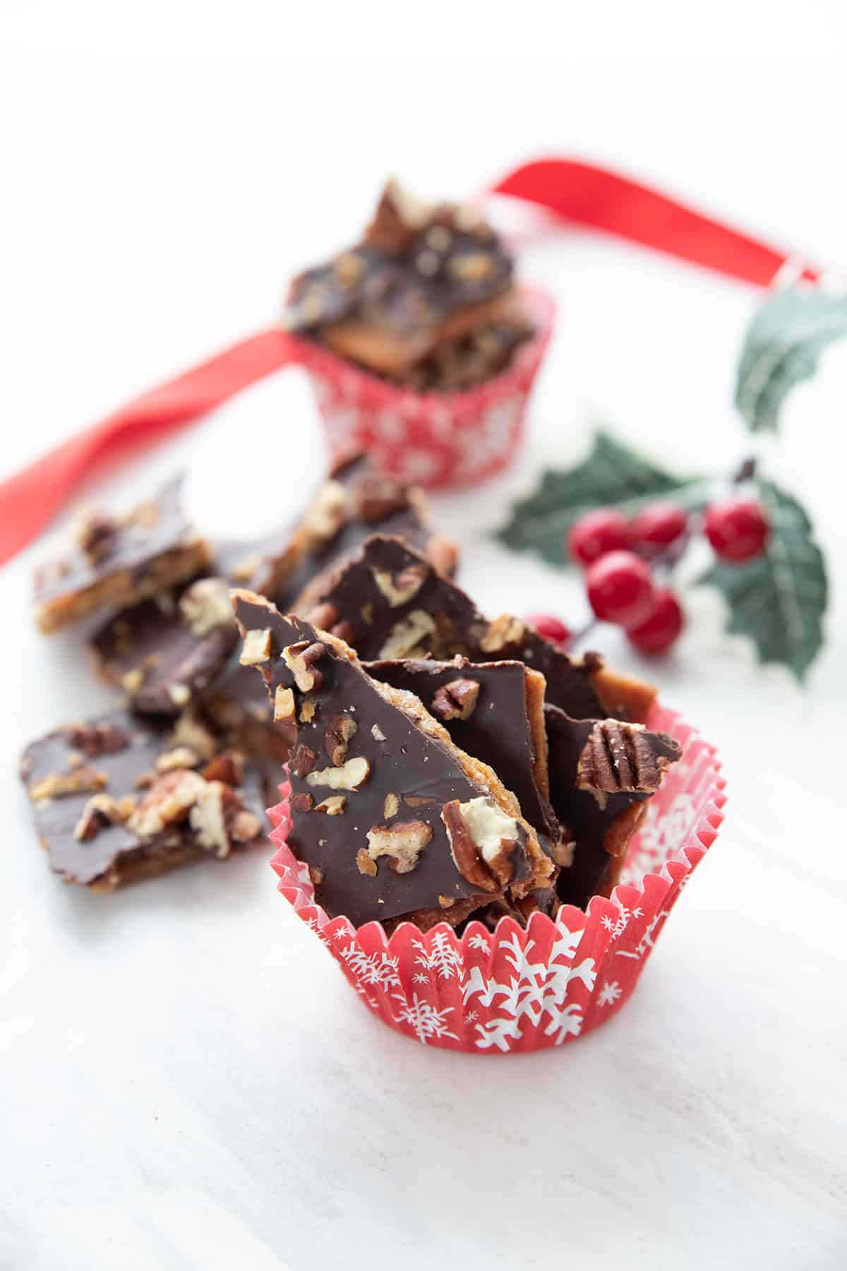 Pieces of keto toffee in a red and white holiday patterned cup.