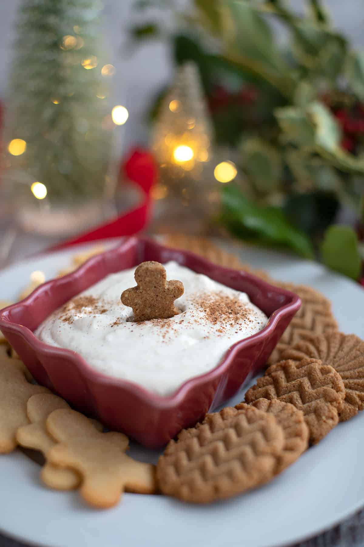 A mini keto gingerbread cookie in a bowl of keto cheesecake dip.