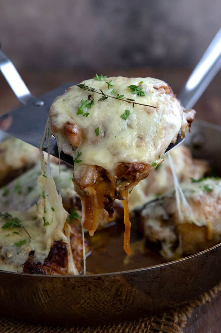 A piece of French Onion Chicken being lifted out of the pan.