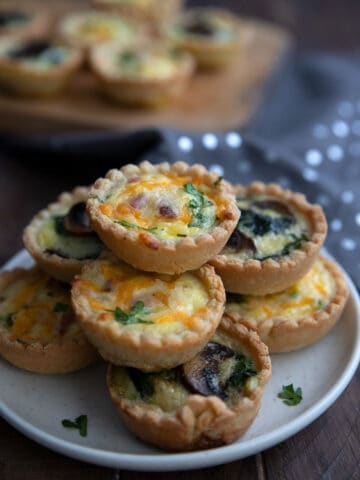 Keto mini quiches piled up on a white plate.