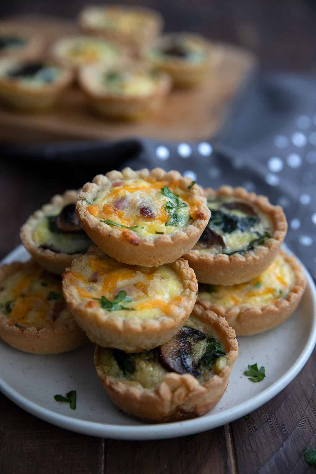 Keto mini quiches piled up on a white plate.