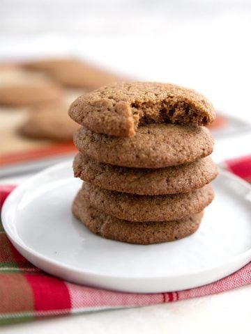 A stack of keto ginger cookies on a white plate over a holiday plaid napkin.
