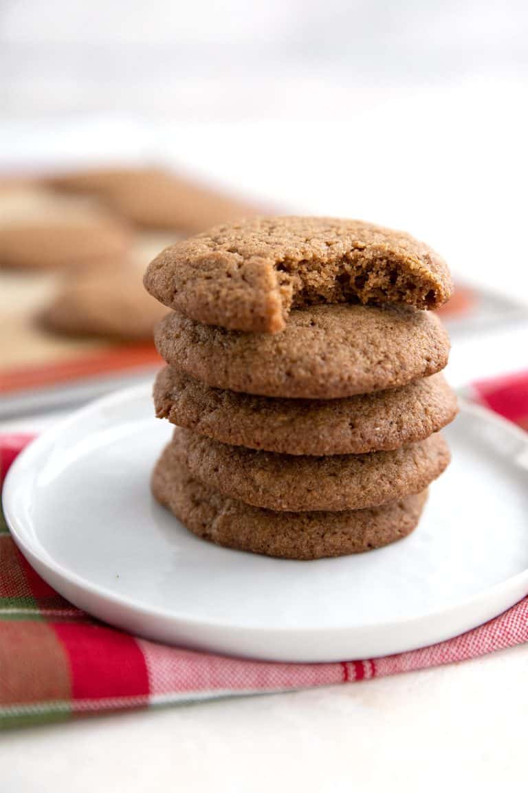 A stack of keto ginger cookies on a white plate over a holiday plaid napkin.